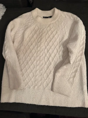 Vit stickad tröja från Lager 157 - Mysig vit stickad tröja från Lager 157 med grovt kabelstickat mönster framtill och på ärmarna. Strl small