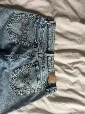Lågmidjad bootcut jeans - Lågmidjade bottcut, i ljusblå jeans. Jeansen har snygga broderade detaljer på bakfickorna.  Jeansen sitter bra på mig i längden som är ca 164, storleken är 36 men skulle säga mer 34/35. Skriv för fler bilder💞 
