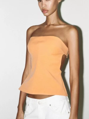 Persikofärgad bandeau tubtopp - Säljer en snygg bandeau tubtopp i persikofärg med lätt utsvängd form. Toppen är axelbandslös och stängs med tryckknappar på insidan. Aldrig använd.