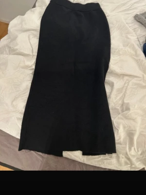 Svart långkjol från Object XS - Säljer en svart långkjol från Object i storlek XS. Kjolen har en rak passform och en snygg slits bak som ger extra rörelsefrihet. Materialet är mjukt och känns lite stickat, perfekt till en cool vardagslook. Enkel midja utan synliga detaljer.