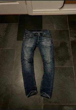 Dondup jeans - Snygga blå jeans från Dondup i storlek 29 med slitna detaljer och klassisk femficksdesign. Jeansen har en rak passform och normal midja, tillverkade i jeansmaterial med cool tvättad look. Perfekt för dig som gillar en avslappnad look.
