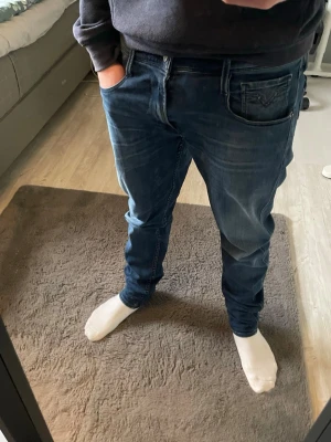 Blå Replay jeans anbass - Säljer ett par blå Replay jeans anbass. Jeansen har klassiska fem fickor, Replay-logga på myntfickan och kontrastsömmar. Materialet är mjukt jeans-tyg i bomull och passformen är normal. Perfekta till en avslappnad stil.