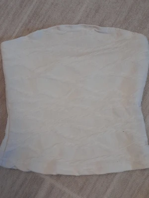 Vit bandeau tubtopp från SHEIN - Säljer en vit bandeau tubtopp från SHEIN i storlek XS. Toppen är ribbad och har en enkel, stilren design utan axelband. Materialet är mjukt och stretchigt, perfekt för varma dagar eller som layering-piece. Finns en liten brun fläck på ryggen men syns inte om man skulle ha en kofta över. !!endast swish +frakt!!