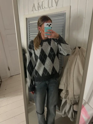 Grå rutig stickad tröja från Freequent - Säljer en stickad tröja från Freequent i storlek XS. Tröjan har ett klassiskt argyle-rutmönster i mörkgrått och ljusgrått, rund halsringning och långa ärmar. Perfekt för dig som gillar en chill och snygg look.