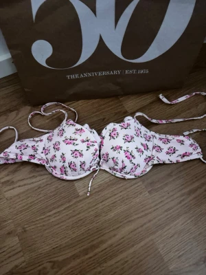 Blommig bikini - Söt bikini med blommigt mönster i rosa. Kuporna är vadderade och har knytband både i ryggen och nacken. Använd en gång