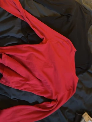 Röd och svart ribbad långärmade tröjor från Cubus - Röd och svart långärmade tröjor från Cubus i storlek 158/164. Tröjorna är ribbad och har en klassisk rund halsringning. Perfekt för dig som gillar enkel och stilren design med en poppig färg. Passar till både jeans och kjol.