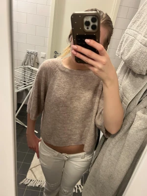  stickad tröja - Mysig croppad stickad tröja i beige ton med rund hals och trekvartsärm. Perfekt för lager på lager och chill dagar. Tröjan har en loose passform och är superenkel att styla till både jeans och kjol.