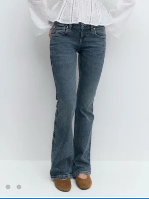 Blå lågmidjade jeans - Snygga blå jeans med bootcut passform och dekorativa broderade sömmar på bakfickorna. Jeansen är använda fåtal gånger och i superbra skick! 