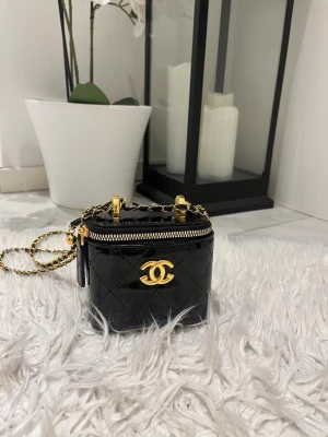 Svart quiltad miniväska  - Supersöt svart miniväska quiltat skinn med guldfärgade detaljer och kedjerem. Väskan har dragkedja upptill och det klassiska CC-loggan framtill. Perfekt för det viktigaste när du vill ha en lyxig touch till din outfit. Hade 2 i lager men nu har jag endast den sista kvar i lager. Så passa gärna på 