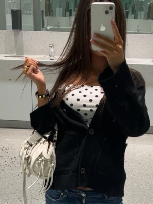 Svart kofta med knappar - Säljer en svart kofta med stora knappar framtill och två fickor. Koftan har en avslappnad passform och är stickad i mjukt material, perfekt att slänga över en topp. Långärmad och enkel att styla till jeans eller kjol.