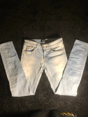Ljusblå  jeans från Replay - Säljer ett par ljusblå  jeans från Replay, modell LUZ. De har klassisk femficksdesign, normalhög midja och är tillverkade i mjukt jeansmaterial. Snyggt slitna detaljer framtill och smal passform hela vägen ner.