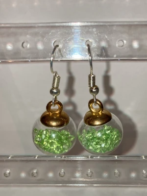 Örhängen  - Handgjorda örhängen som görs av mig. Med gröna julkulor i glas. Frakten är ca 22-100kr beroende på vikten på produkten . Kontakta mig om du vill köpa.