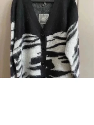 Zebramönstrad kofta från GCDS - Säljer en fluffig och oversized zebramönstrad kofta från GCDS i svart och vitt. Koftan har v-ringning, knappar framtill och är stickad i ett mjukt material som känns lyxigt. Perfekt för dig som vill sticka ut med en trendig look. Storlek Onesize, passar bäst M/L men snygg även som oversize  på mindre storlek, kolla sista bilden . Sista bilden är ej tröja som jag säljer