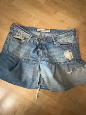 Blå jeanskjol Hollister  - Säljer en blå jeanskjolen jag har sytt själv med ett par jeans från Hollister. Finns två knappar på den och den som syns i bilden är påsydd för att den ska bli mindre. Så den passar alla från S/M beroende på vilken knapp man använder!!! 💗tryck gärna på köp nu!