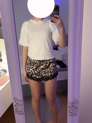 Vit blus med puffärm och broderi - Säljer en söt vit blus med puffiga, broderade ärmar och rund hals. Blusen har korta ärmar med hålbroderi och en avslappnad passform. Perfekt för dig som vill ha en feminin och trendig topp till sommaren.