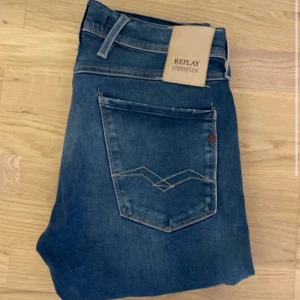 Replay Hyperflex blå jeans straight fit - Säljer ett par Replay Hyperflex jeans i klassisk blå tvätt med slitna detaljer och raka ben. Jeansen har fem fickor, bälteshällor och snygga kontrastsömmar på bakfickorna. Materialet är stretchigt jeans för extra komfort och passform.