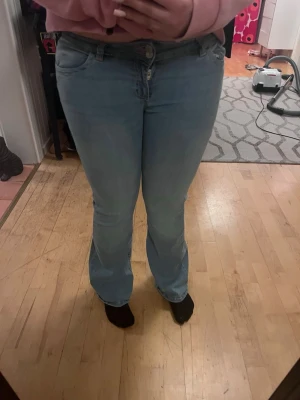 Ljusblå bootcut jeans med rosa broderi - Säljer ett par ljusblå jeans med bootcut passform och snyggt broderi i rosa på bakfickorna. knapp och dragkedja framtill. Jag är 165cm och dom passar perfekt i längd! Men passar även upp till 175cm ish. 