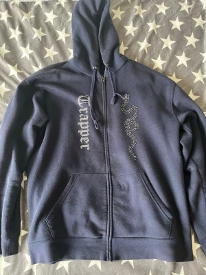 Made by trappers zip hoodie - Mörkblå made by trappers hoodie, rätt så använd så därför de billiga priset. Lite solskada men syns inte för tydligt. Alla rhinestones och liknande är kvar 