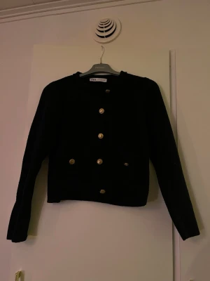 Marinblå kofta med guldknappar från Zara - Säljer en marinblå, stilren kofta från Zara med långa ärmar och snygga guldknappar framtill. Koftan är stickad. 