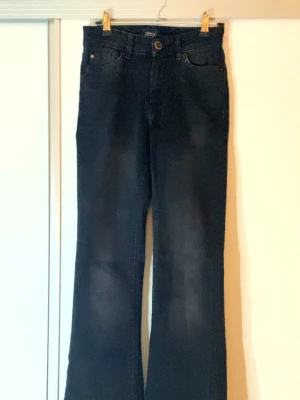 Svarta bootcut jeans från Only - Säljer ett par svarta bootcut jeans från Only. Jeansen har klassisk femficksdesign, hög midja och är tillverkade i stretchig denim för skön passform. Snyggt utsvängda ben 