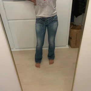 esprit bootcut jeans med broderi bak - Snygga ljusblå jeans från esprit med bootcut passform och låg midja. Jeansen har slitna detaljer, broderi på bakfickan och klassisk femficksdesign. Materialet är mjukt jeans-tyg med dragkedja och knapp framtill. vintage och utgått ur sortimentet 