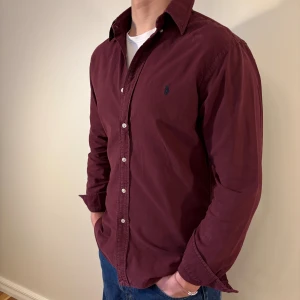 Vinröd Ralph Lauren skjorta - Nu säljer vi ännu en snygg polo skjorta som passar till alla tillställningar! Du ska kunna uttrycka stil utan att det kostar för mycket!🕺🍾💼🤩  Storlek👔: M Nypris💰:  ca 1399 kr