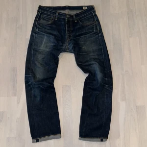Selvage Levis Jeans - Levi's 501 jeans i mörkblå tvätt med klassisk rak passform. Tillverkade av White Oak Cone Denim. Jeansen är i topp skick och har snygga slitningar och man vill göra mer är de bara upp till än!