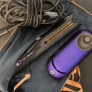 Dyson Corrale Hårplattång - Snygg Dyson Corrale hårplattång i lila med original laddare och fodral. Plattången är i mycket gott skick, inga synliga repor eller skador. Perfekt för att styla håret med flexibla plattor och trådlös användning. Laddstation och kabel medföljer. Nypris 5000kr