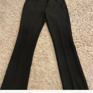 Svarta bootcut kostymbyxor BikBok - Snygga svarta kostymbyxor från BikBok i storlek 38. Byxorna har bootcut-ben och låg midja  med pressveck framtill 