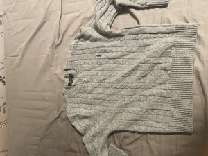 Grå kabelstickad tröja Polo Ralph Lauren - Snygg grå kabelstickad tröja från Polo Ralph Lauren i storlek S. Tröjan har rund hals, ribbade muddar och ett diskret broderat logomärke på bröstet. Perfekt för dig som gillar klassisk stil med en modern touch.