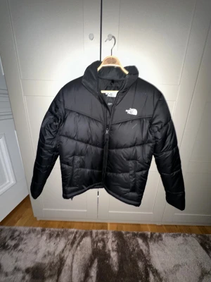 Helt ny‼️Svart pufferjacka från The North Face - Säljer den här pufferjacka från The North Face med klassisk logga på bröstet och ryggen.Den är helt ny, fick den i jul klapp och va för stor sedan gillade jag inte den.Aldirg använd‼️ Jackan har hög krage, quiltad design och dragkedja framtill. Perfekt för kalla dagar och har en clean, stilren look som funkar till streetwear.Ny pris 2500 kr. Skriv vid minsta fundering😀