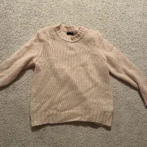 Ljusbeige stickad tröja från GANT - Supermysig ljusbeige stickad tröja från GANT i storlek XS. Tröjan har en rundad hals, ribbade muddar och är stickad i ett fluffigt material som känns både mjukt och luftigt. Perfekt för dig som gillar en enkel och clean look.