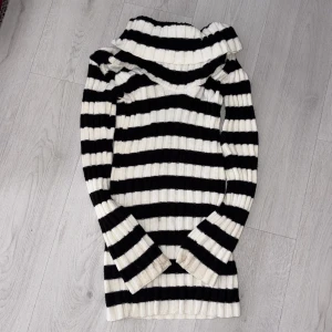 Svartvit randig polotröja Figaro - Säljer en ribbstickad polotröja från Figaro Design i svart och vitt med breda ränder. Tröjan har en stor, mysig polokrage och långa ärmar. Perfekt för dig som gillar klassisk stil med en twist. Passar dig som vill ha något både bekvämt och snyggt. Off shoulder!!!!