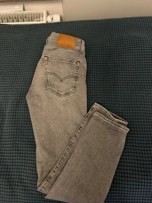 Grå Levi's 511 jeans straight fit - Snygga grå Levi's 511 jeans med straight fit och klassisk femficksdesign. Jeansen har en ljusgrå tvätt, läderpatch bak och den ikoniska röda Levi's-taggen på bakfickan. Passar dig som gillar en smal siluett och stilren look.