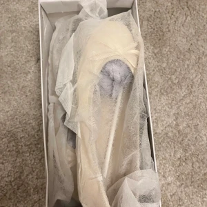 Beige ballerinaskor med rosett - Snygga beige ballerinaskor med rund tå och en söt rosett framtill. Skorna har en platt sula och är tillverkade i syntetmaterial som ger en mjuk och stilren look. Helt oanvända alltså i nytt skick