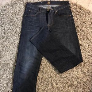 Mörkblå jeans från Lee - Snygga mörkblå jeans från Lee med klassisk femficksdesign och kontrastsömmar. Jeansen har rak passform och normal midja, tillverkade i slitstarkt denimtyg. Perfekta för dig som gillar stilrena och tidlösa jeans.
