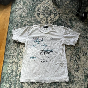Vit Billabong t-shirt med tryck - Vit t-shirt från Billabong med coolt grafiskt tryck och logga i svart och turkos på framsidan. Klassisk passform med rund hals och korta ärmar. Perfekt för en avslappnad streetstil.