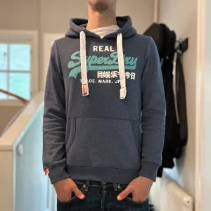 Superdry Hoodie - Blå Superdry hoodie i mycket bra skick🙌🏽| Storlek: S | Jag är 182cm och väger 65kg📏| Vid frågor eller diskussion om pris är det bara att skriva ✍🏼 | Frakt inom 48h📦