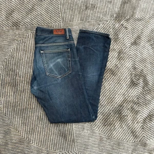Mörkblå jeans från Acne Studios - Snygga mörkblå jeans från Acne Studios med klassisk femficksdesign och diskreta slitningar. Jeansen har raka ben och normal passform, tillverkade i slitstarkt denim. Perfekta för dig som gillar en stilren och tidlös look.
