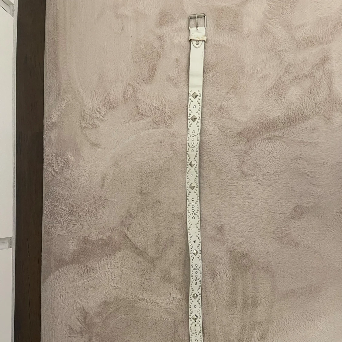 Vit bälte med nitar och hålmönster