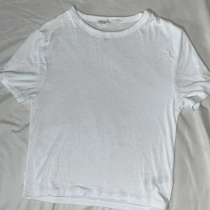 Vit basic t-shirt från Primark - En enkel vit t-shirt från Primark Cares i storlek S. Modellen är klassisk med rund hals och korta ärmar, tillverkad i mjuk bomull. Perfekt för dig som gillar minimalistisk stil och vill ha en skön och lätt t-shirt i garderoben. Lite croped samt en liten smink fläck!