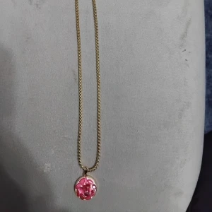 Guldhalsband med rosa stenar - Unikt halsband med guldfärgad kedja och rund berlock. Berlocken har inslag av rosa stenar som ger ett färgstarkt och personligt uttryck. Perfekt för dig som vill sticka ut med accessoarer som känns både trendiga och lekfulla. Köpte från Turkiet i somras 