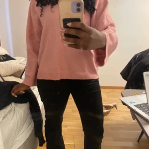 Ljusrosa stickad tröja med vida ärmar - Mysig ljusrosa stickad tröja med rund hals och vida, långa ärmar. Tröjan har en avslappnad passform och ribbade muddar vid ärmslut och nederkant. Perfekt för dig som gillar en enkel men söt look.