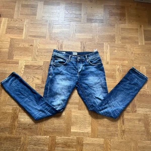 Jack & Jones jeans slim fit - Snygga blå Jack & Jones  jeans med klassisk femficksdesign och smal passform. Jeansen har en något tvättad look med slitningar och kontrastsömmar. Perfekta för dig som gillar en modern och stilren denimstil.