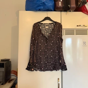 Blommig blus från Odd Molly - Supersöt blus från Odd Molly med svart botten och små rosa blommor samt paisleymönster. Blusen har v-ringning med knappar och långa ärmar. Tunn och luftig känsla, perfekt för dig som gillar boho-vibe och detaljerade mönster. Storlek 1 som enligt deras storleksguide motsvarar en storlek S. Men kanske är något mellan S/M. SAMPLE. Mycket fint skick, jag hittar inga synliga anmärkningar eller defekter. 