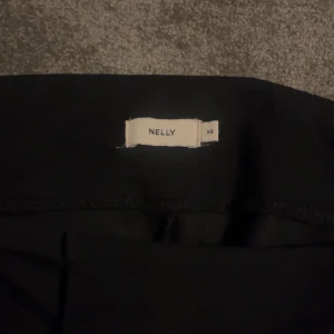 Svarta bootcut byxor från Nelly XS - Svarta byxor från Nelly i storlek XS med bootcut-modell. Sitter tajt över låren och släpper ut vid vaden för en snygg siluett. Mjukt och stretchigt material som är bekvämt att bära hela dagen. Perfekta för dig som gillar en stilren look.