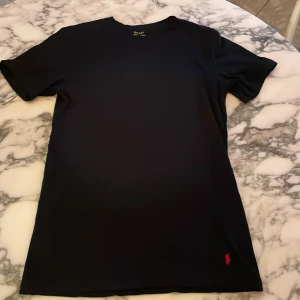 Ralph lauren t-shirt - Svart t-shirt från Polo Ralph Lauren i slim fit med klassisk röd broderad logga nertill. Tillverkad i 100% bomull och har korta ärmar. Enkel och stilren design som passar perfekt till jeans eller shorts. Slim fit, passar storlek S även😃pris kan diskuteras!!!