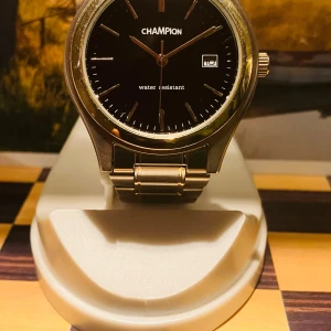 Champion Herr klocka - Stilren klocka från Champion med svart urtavla och silverfärgat armband i metall. Urtavlan har minimalistiska index och datumvisning . Boetten är rund och armbandet har en klassisk länkdesign. Perfekt för dig som gillar enkel och snygg design. Nytt batteri, fungerar kanonbra!