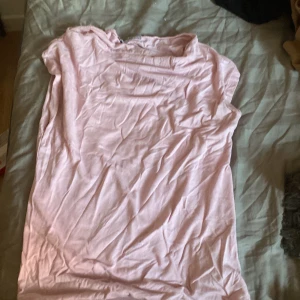 Ljusrosa t-shirt från 157, XS - Säljer en enkel ljusrosa t-shirt från 157 i storlek XS. T-shirten är ärmlös och har en klassisk rund hals. Materialet är mjuk bomull som känns skönt mot huden. Perfekt för dig som gillar basic och stilrena plagg i din garderob.