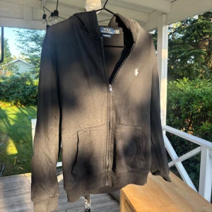 Raffe tröja. Storlek m men sitter som xs - Svart hoodie från Polo Ralph Lauren i bomull med dragkedja framtill, huva och två stora fickor. Klassisk vit logga broderad på bröstet och ribbade muddar. Custom fit-modell som sitter snyggt och avslappnat. Storlek M skrivet men passar XS, folk runt 170-175. Mvh